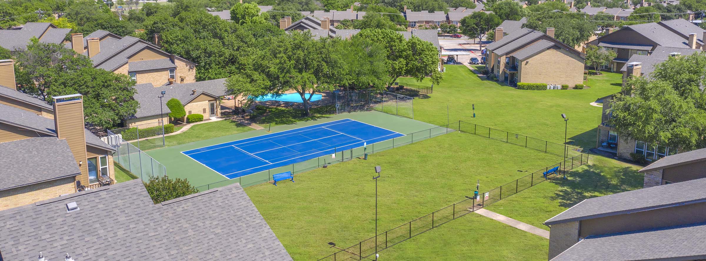 Drone shot of a tennis/ pickleball court that is nearby a pet playground.